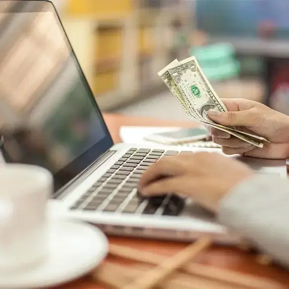 Business owner holding money while on computer